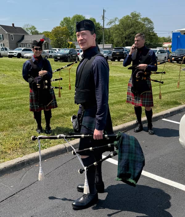 Kendall Giles holding bagpipes with two members of the band just prior to a performance